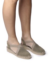 Espadrilky s vrchní částí z zelené tkaniny a béžovými elastickými překříženými pásky. Mají jutu obalovou podešev s klínem. Povrch je hladký s tkaným finišem.