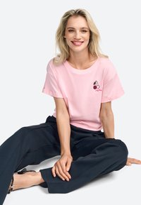 Lyserød kortærmet t-shirt med broderet kirsebærdesign; afslappet pasform, rund halsudskæring, blødt bomuldsstof. Bæret sammen med marineblå bredbenede bukser.