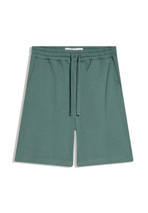 Zeleni kratki hlači z elastičnim pasom, vrvico in stranskimi žepi, izdelani iz mehkega blaga, položeni na ravno na belem ozadju.