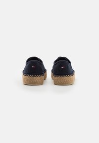 Mörkblå kanvas slip-on skor med flätade jute-sulor. Har en subtil logotyp detalj på hälen. Öppen bakdesign för enkel påtagning.