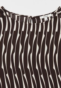 Primo piano di tessuto a righe ondulate verticali bianco e nero con scollo rotondo e piccola etichetta del marchio Opus taglia 36.