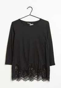 Musta pitkähihainen paita, jossa on pitsireunus kukkakuviolla. Pehmeää kangasta ja pyöreä pääntie. Roikkuu mustalla metallivaatetelineellä.