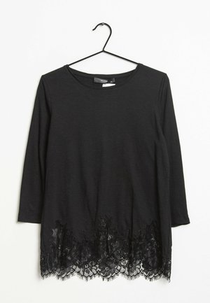 Top nero a maniche lunghe con orlo in pizzo e motivo floreale. Tessuto morbido e scollatura rotonda. Appeso a un gancio metallico nero.