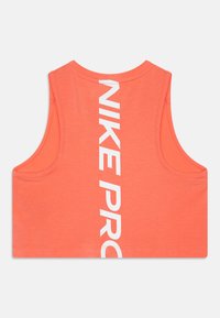 Nike Pro urheilu tank top, koralli väri, hihaton malli, jossa on pystysuora valkoinen logo selkäpuolella. Valmistettu pehmeästä, joustavasta kankaasta.