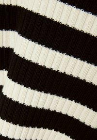 Czarny i kremowy pasiaste dzianinowe tkaniny o prążkowanej teksturze. Zawiera na przemian szerokie paski z precyzyjnym szyciem i spójnym wzorem.