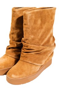 Stivali in suede beige con un design morbido, dotati di punta rotonda e superiore testurizzato. Le suole sono leggermente elevate e realizzate in gomma.