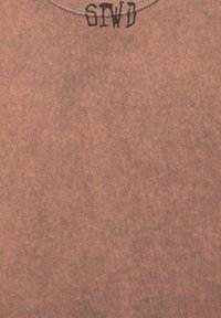 T-shirt en coton marron avec une finition douce et texturée. Présente un col rond et la mention "SPWD" en lettres noires au niveau du col. Design minimaliste.