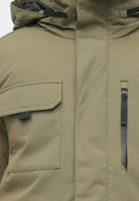 Olivgrüne, isolierte Jacke mit hohem Kragen, Fronttasche und Reißverschluss-Brusttasche; gefertigt aus einem glatten, strapazierfähigen Stoff.