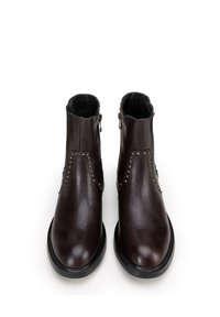 Brązowe skórzane botki za kostkę o gładkim wykończeniu, z ozdobnymi ćwiekami po bokach i czarną gumową podeszwą. Zawierają zamek błyskawiczny po bokach.