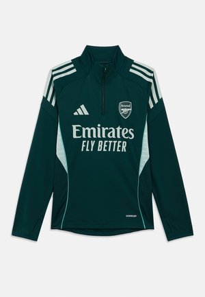 Veste d'entraînement vert foncé avec col montant, demi-fermeture éclair, arborant les bandes et logo Adidas blancs, ainsi que le texte « Emirates Fly Better » en blanc.