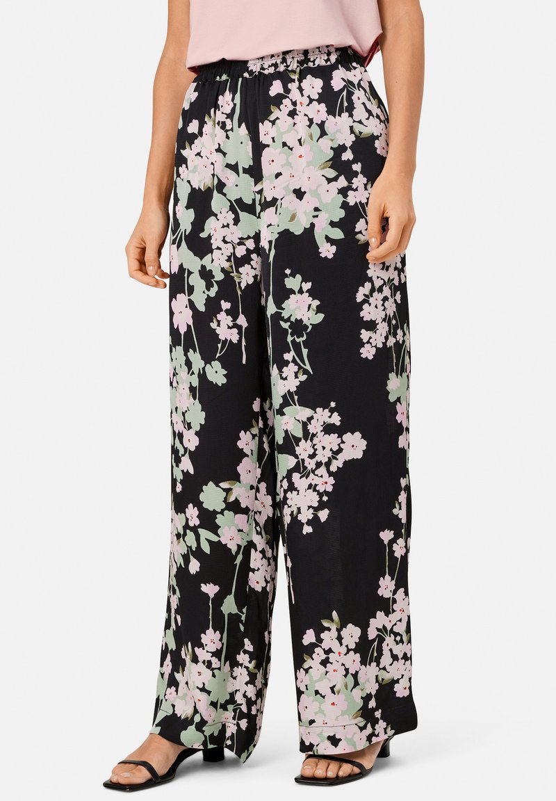 Pantalon noir à motif floral à coupe large, avec un motif floral rose et vert, taille élastique et tissu léger.