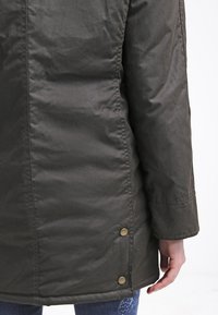 Padded dark green coat featuring a straight cut, large buttons at the side, and a textured material. Back view with no visible logos.