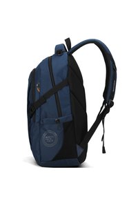 Zaino blu con un mix di tessuti texture e lisci, multiple cerniere, dettagli in rete e una patch a forma di cerchio sul davanti.