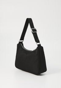 Borsa a spalla nera realizzata in tessuto morbido, con chiusura a zip argento, tracolla regolabile e forma angolare con superficie liscia.