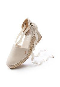 Espadrilla beige con tomaia in tela, suola in juta intrecciata e lacci in nastro. Presenta una punta arrotondata e cuciture tono su tono.