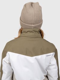 Egy barna kötött sapkát és egy barna-fehér Brunotti dzsekit viselő személy hátulról látható, egyszerű háttér előtt.