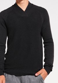 Svart stickad tröja med sjalkrage, åtsittande ärmar och ribbad nederkant. Tillverkad av mjukt tyg med strukturerad yta.