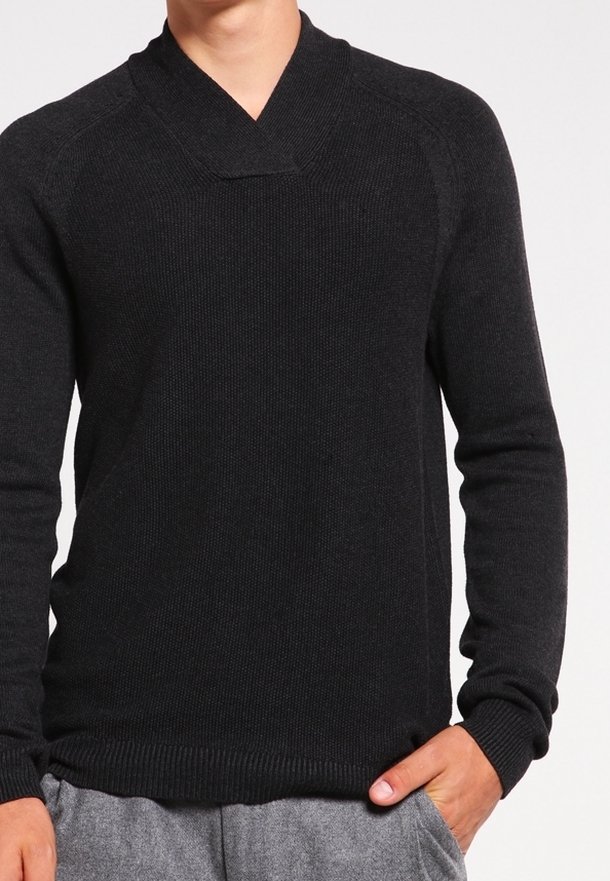 Svart stickad tröja med sjalkrage, åtsittande ärmar och ribbad nederkant. Tillverkad av mjukt tyg med strukturerad yta.