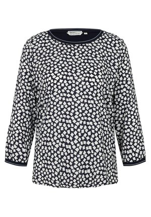 Navy blue long-sleeve top featuring a geometric white pattern, round neckline, and a textured fabric with contrasting cuffs.