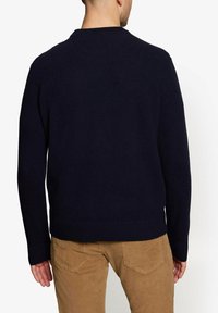 Mørkeblå strikket sweater med rund hals og lange ærmer, lavet af blødt materiale. Sammen med beige fløjlsbukser.