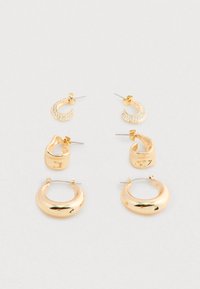 Tres pares de pendientes de aro de oro en estilos pequeño con perno, mediano grueso y grande liso dispuestos sobre un fondo claro y simple.