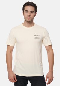 Cremefarvet bomulds t-shirt med rund halsudskæring, korte ærmer og et lille grafisk print med ordet "PETROL" og en motorcykel.