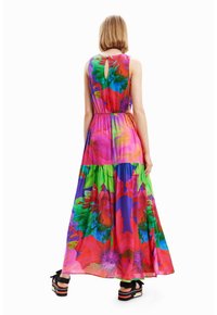 Robe maxi à imprimé floral vibrant avec des teintes de rose, vert et violet. Dos à lacer, taille cintrée et ourlet en cascade fluide.