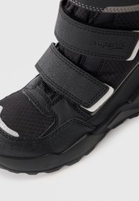 Czarne buty sportowe z teksturowaną cholewką, z trzema paskami na rzepy, panelami z siateczki oraz trwałą gumową podeszwą. Akcentowe przeszycia w kolorze szarym.