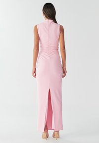 Prilegla roza obleka iz raztegljivega materiala z visokim ovratnikom, nabrano obdelavo na zadnji strani in središčno razporko na robu.