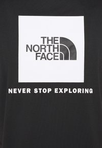 Czarny bawełniany t-shirt z białym kwadratem z logo "THE NORTH FACE" oraz frazą "NEVER STOP EXPLORING" w pogrubionych białych literach.