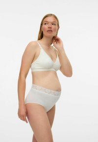 Bralette couleur crème en tissu doux, avec des bordures en dentelle et des bretelles ajustables. Associé à une culotte taille haute assortie avec une taille en dentelle.