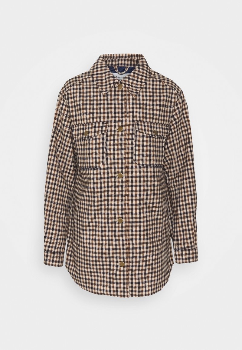 Camisa de franela a cuadros en tonos marrón y crema, con cuello, dos bolsillos en el pecho y botones de presión en tono dorado. Mangas largas y dobladillo curvado.