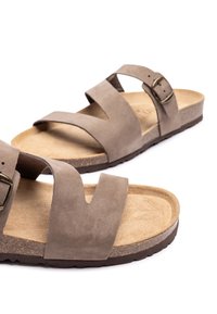Bruine suède sandalen met twee gekruiste banden en een verstelbare metalen gesp. Kurken voetbed en een gestructureerde rubberen zool, die comfort en duurzaamheid bieden.