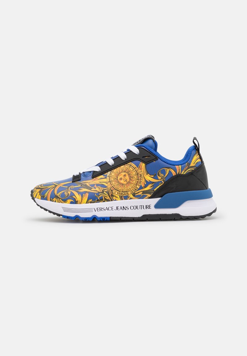 Baskets bleu et or Versace Jeans Couture avec lacets blancs, emblème soleil, motifs baroques décoratifs et détail de semelle blanche à la marque.