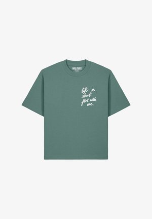 Zielona koszulka z krótkim rękawem z białym, odręcznym napisem na piersi: "życie jest krótkie, flirtuj ze mną."