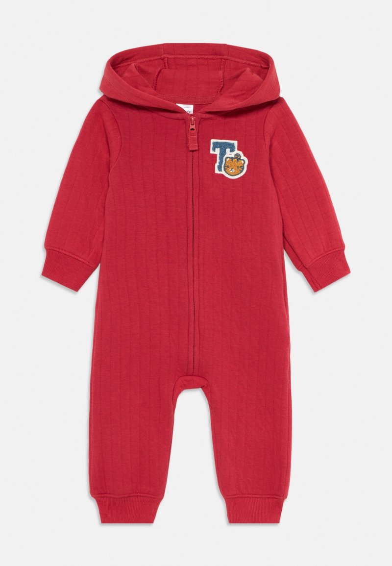 Grenouillère matelassée rouge avec capuche, fermeture éclair à l'avant et un patch bleu en forme de "T" avec un petit visage d'ours sur la poitrine.