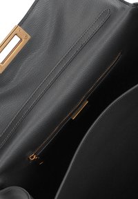 Interno di una borsa a tracolla nera in pelle con zip e accessori in tono dorato. Caratterizzata da una texture liscia, un compartimento principale e una tasca con zip.