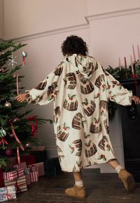 Hættetæppe med beige stof prydet med et trykt mønster af leopardprint-desserter og kristtornblade. Gulvlængde og løstsiddende design.