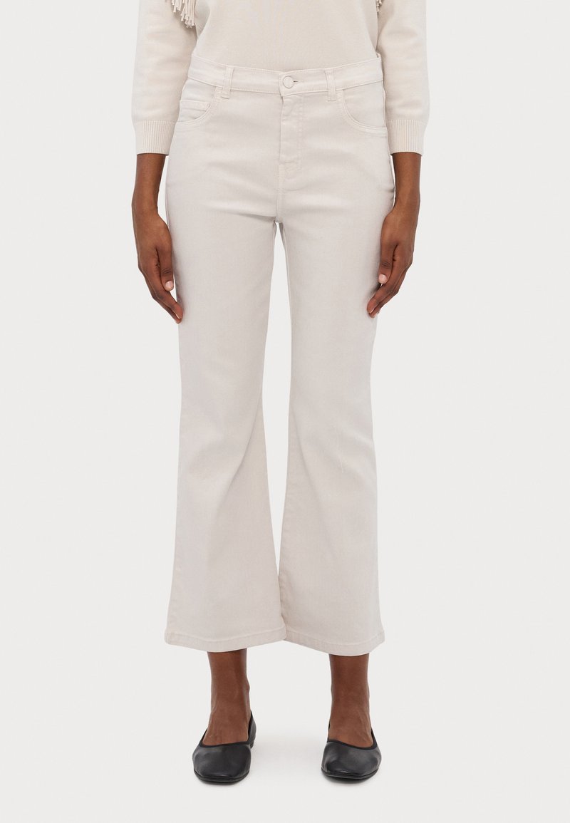 Jeans flare em bege claro feitos de denim. Apresentam cinco bolsos, passantes para cinto e fecho com botão. Textura suave com um design de perna larga.