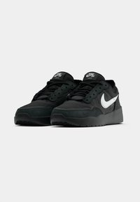 Μαύρα παπούτσια Nike SB Zoom με υφή στο επάνω μέρος, αντίθετο λευκό σήμα swoosh και ανυψωμένη σόλα. Σχεδίαση με κορδόνια και επένδυση στον γιακά.