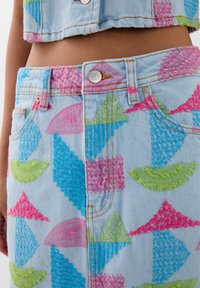 Gonna in denim azzurro con ricami multicolori a triangoli e semicirchi. Presenta una chiusura con bottone e motivi testurizzati.