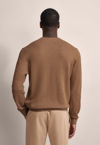 Brauner Strickpullover mit einem strukturierten Zickzackmuster, gerippten Bündchen und Saum. Verfügt über einen klassischen Rundhalsausschnitt und eine lockere Passform.