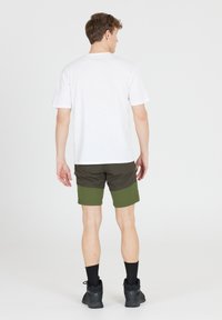 Herreoutfit med en ensfarvet hvid t-shirt og multicolore shorts i mørkegrøn og olivengrøn, parret med sorte sokker og sko.
