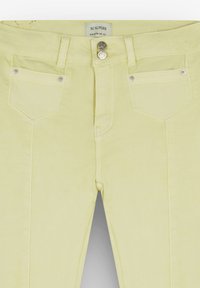 Pantaloni gialli con tasche frontali, chiusura a due bottoni argento e dettagli di cucitura. Realizzati in tessuto elasticizzato, presentano una texture liscia.