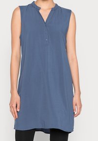 Ärmlose tunika i blått med V-ringning, knappstängning och veckade detaljer, tillverkad av mjukt och lätt material.