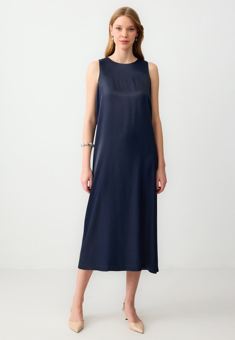 Navyblaues ärmelloses Kleid mit geradem Schnitt, glatter Textur, das bis zur Mitte der Waden reicht, kombiniert mit beigen spitzen High Heels.