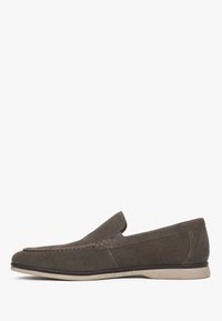 Dark brown suede slip-on loafer with a flat beige sole and minimal stitching detail on a white background.