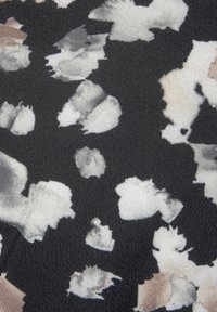 Geweven stof met een abstract patroon van zwarte, witte en beige vlekken. Het materiaal heeft een lichte glans.