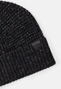 Gorro de malha preto com um padrão texturizado e manchas coloridas. Inclui um patch de couro preto com o logotipo na borda.