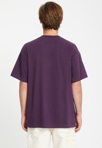 Lilla, kortærmet bomulds T-shirt med en afslappet pasform. Har en rund hals og en glat tekstur, set fra ryggen.
